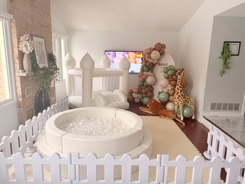 Overhead view of a modern nursery with a white round ball pit surrounded by a white picket fence, decorated with stuffed animals and toys